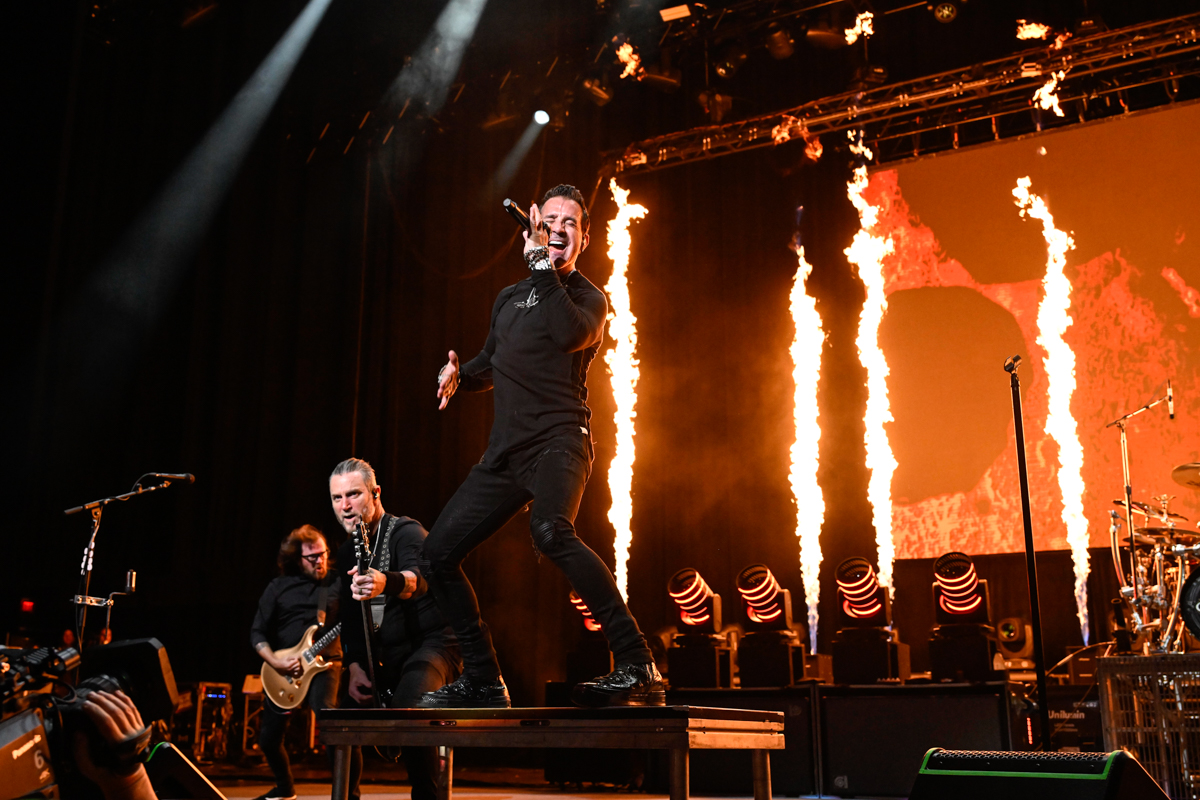 Photo of a band performing on stage with pyrotechnics in the back.