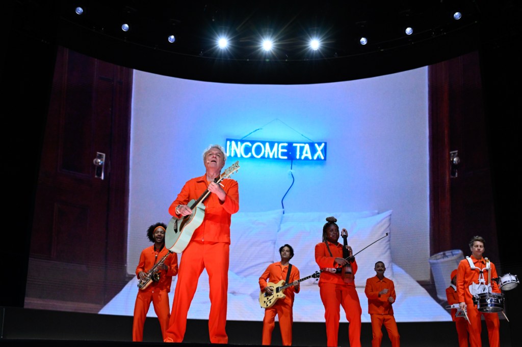 A band on stage wearing orange jumpsuits 
