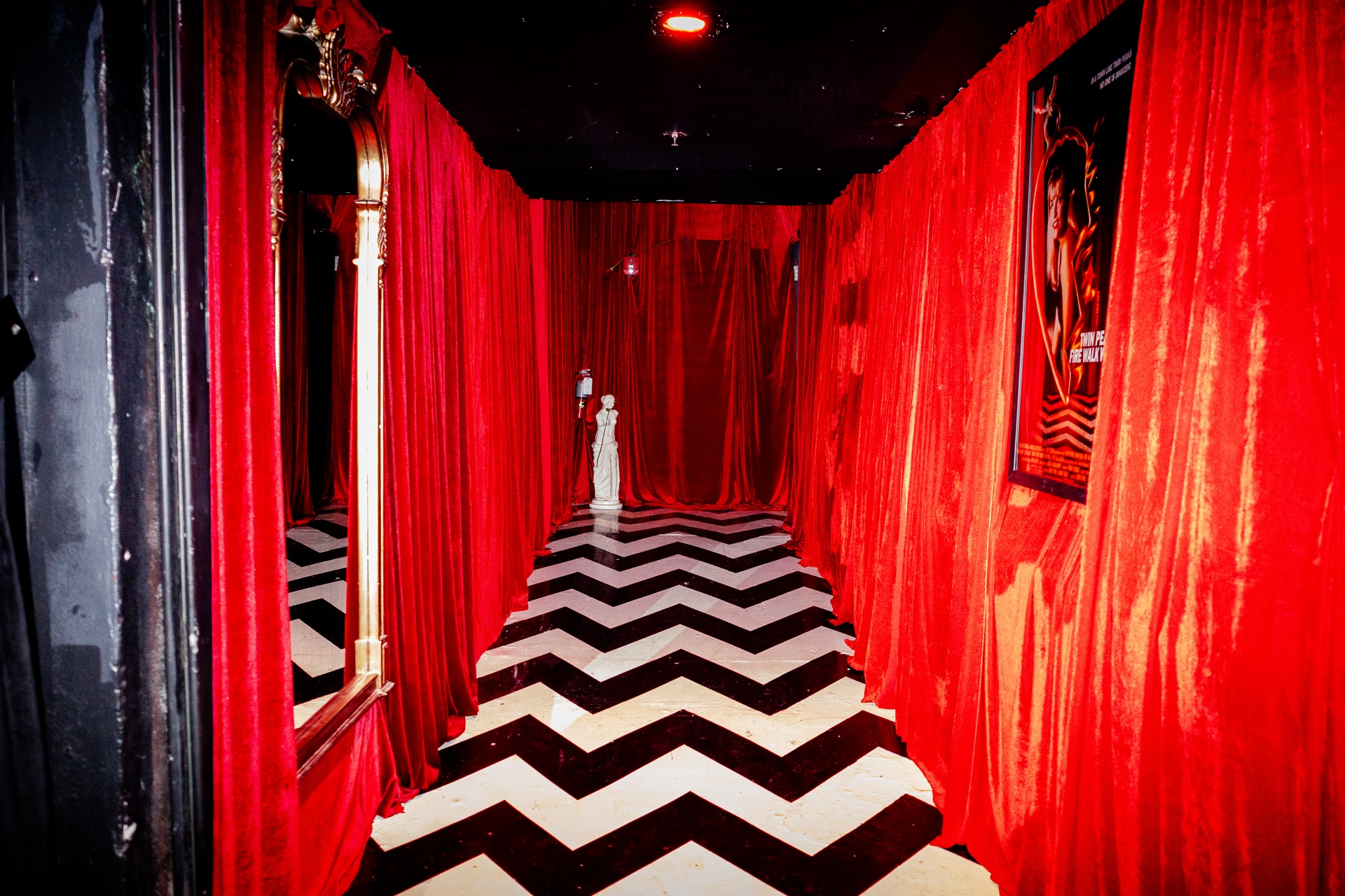 A photo pf a room with a corridor with black and white floors and red walls.