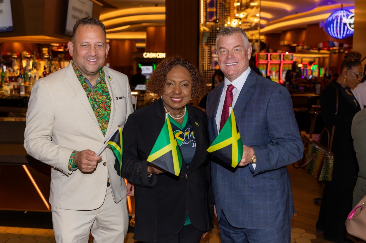 A group of three people holding Jamaican flags