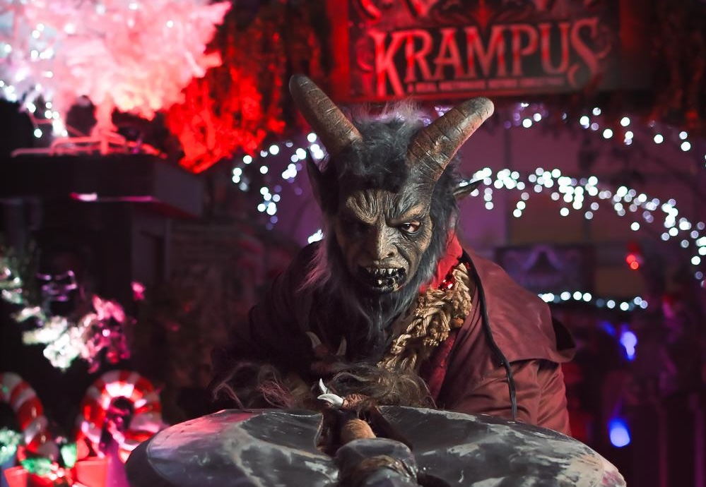 photo of a person in a Krampus costume holding a spear on a platter beneath a sign reading, "Krampus"
