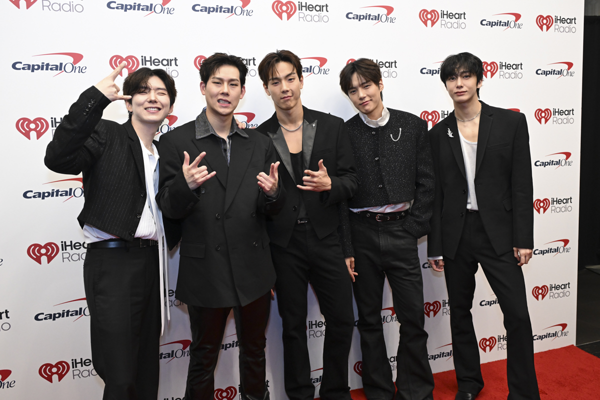 photo of a group of Korean singers in front of a step and repeat.