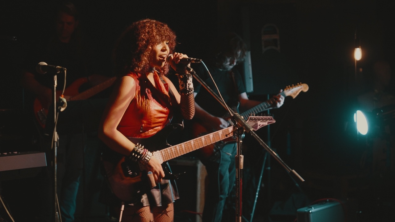 Photo of a young woman on stage playing guitar.