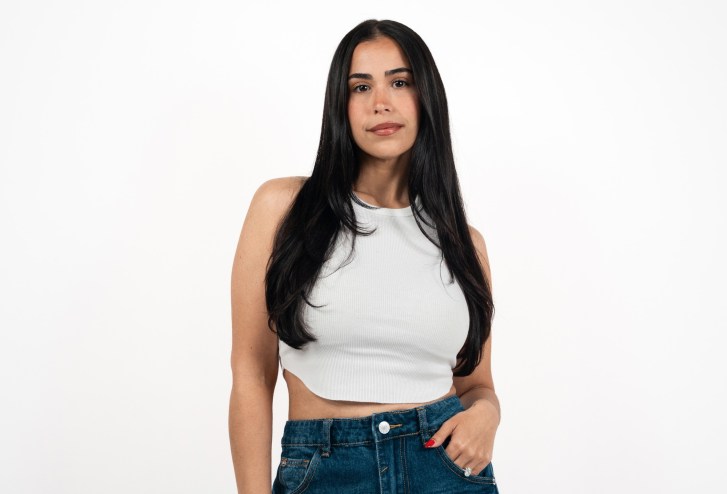photo of a woman with long black hair in a white crop top and jeans posing in front of a white backdrop