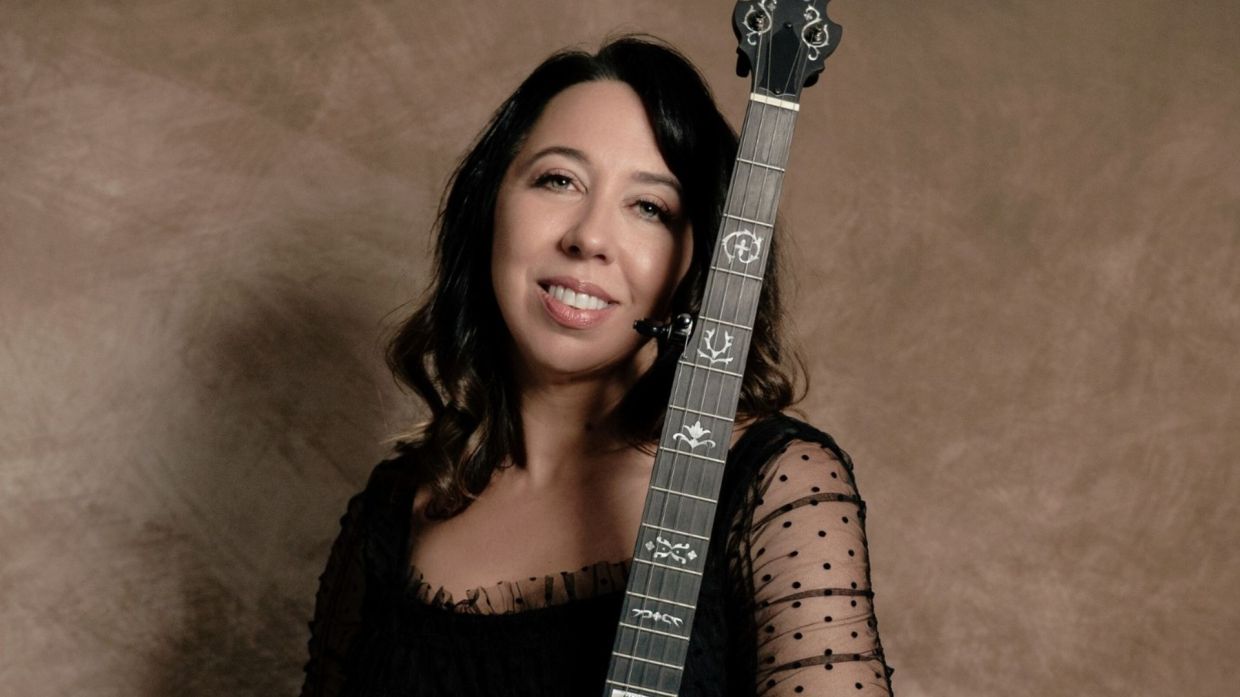 A photo of woman holdin a banjo