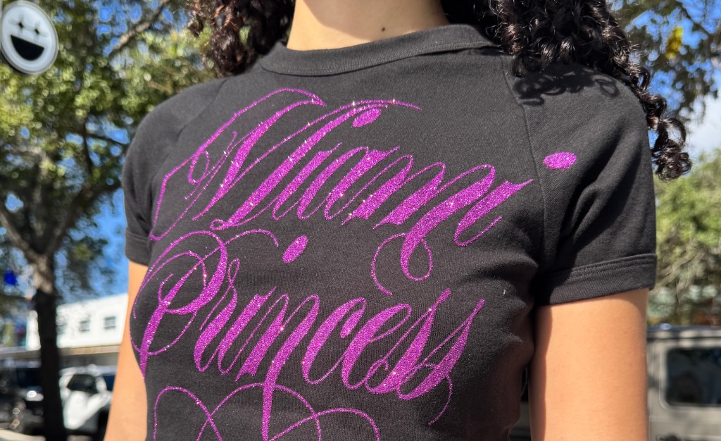 photo of a woman wearing a black T-shirt reading "Miami Princess" in magenta cursive font