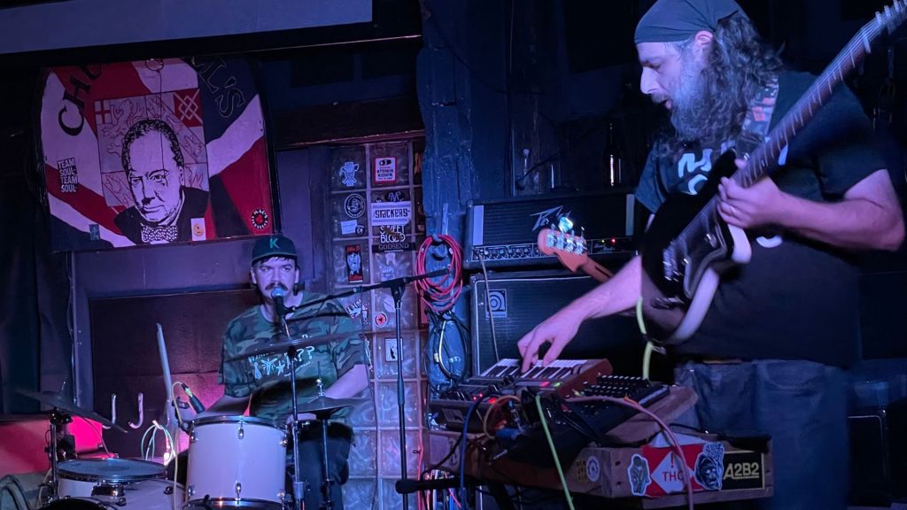 Photo of a drummer and a guitar player on stage.