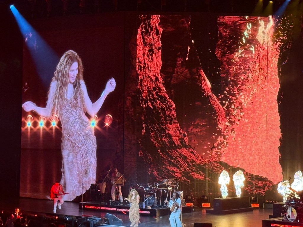 photo of Shakira bellydancing onstage with a Jumbotron projecting her image behind her