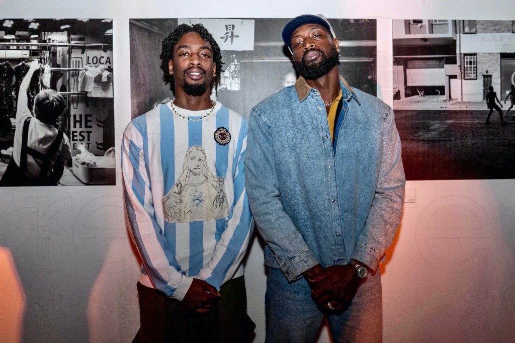 photo of basketball players Zaire and Dwyane Wade posing in front of black-and-white photos