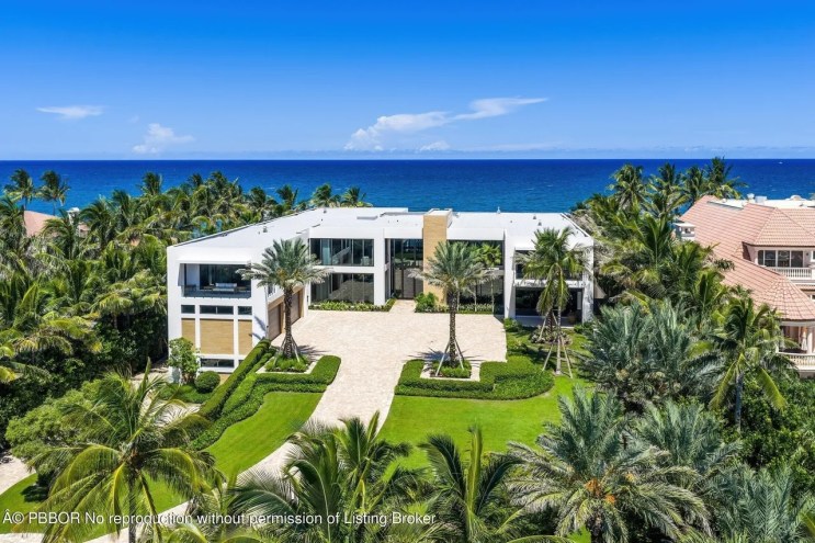 a white mansion sits on a beachfront property surrounded by palm trees