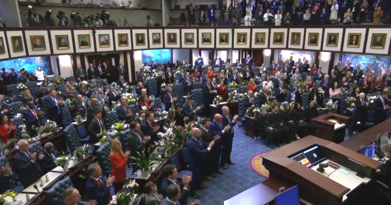 State legislators applauding and standing in the Florida Representatives chambers