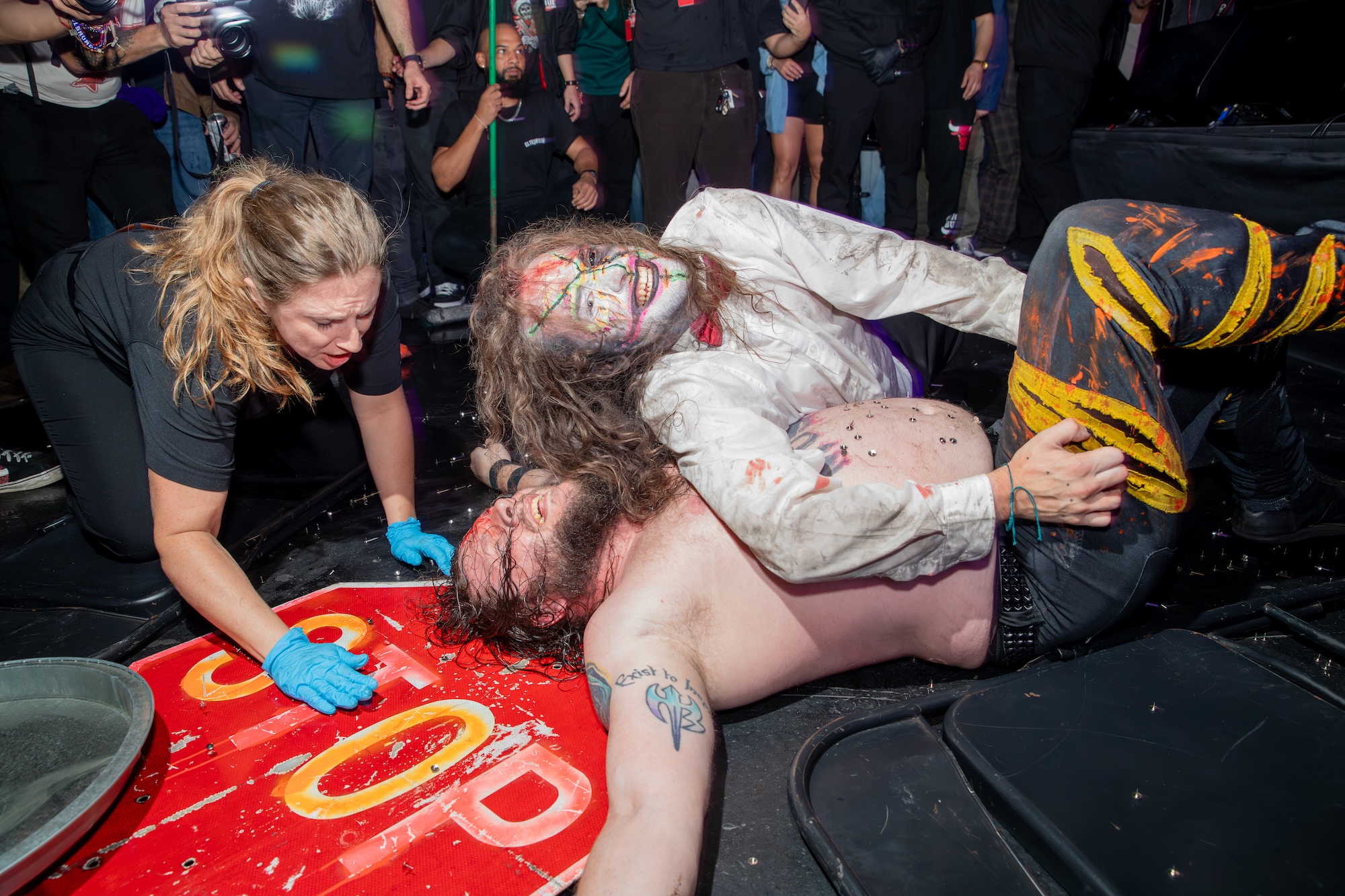 Photo of two wrestlers on the floor over a stop sign .