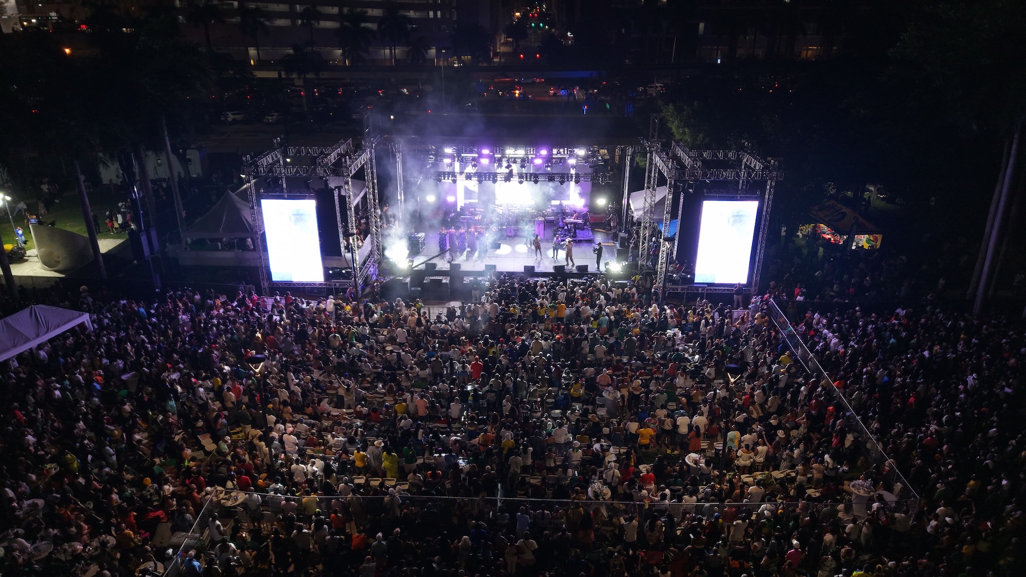 Photo of a stage at a festival at night and a lot of people in the crowd