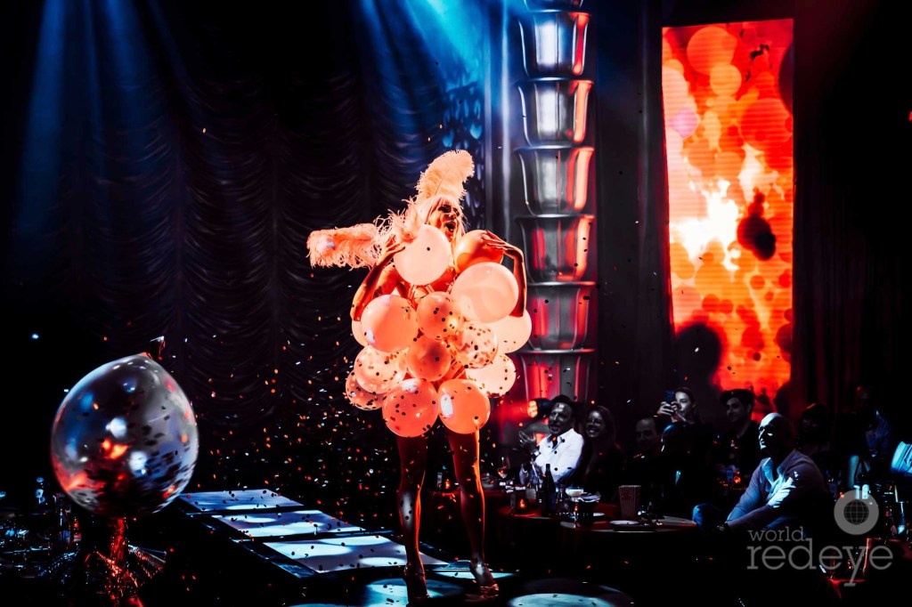 photo of a performer on a stage wearing a dress made of balloons