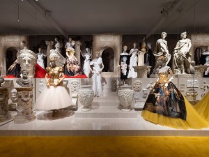 photo of ornate dresses on mannequins on a platform inside an art gallery