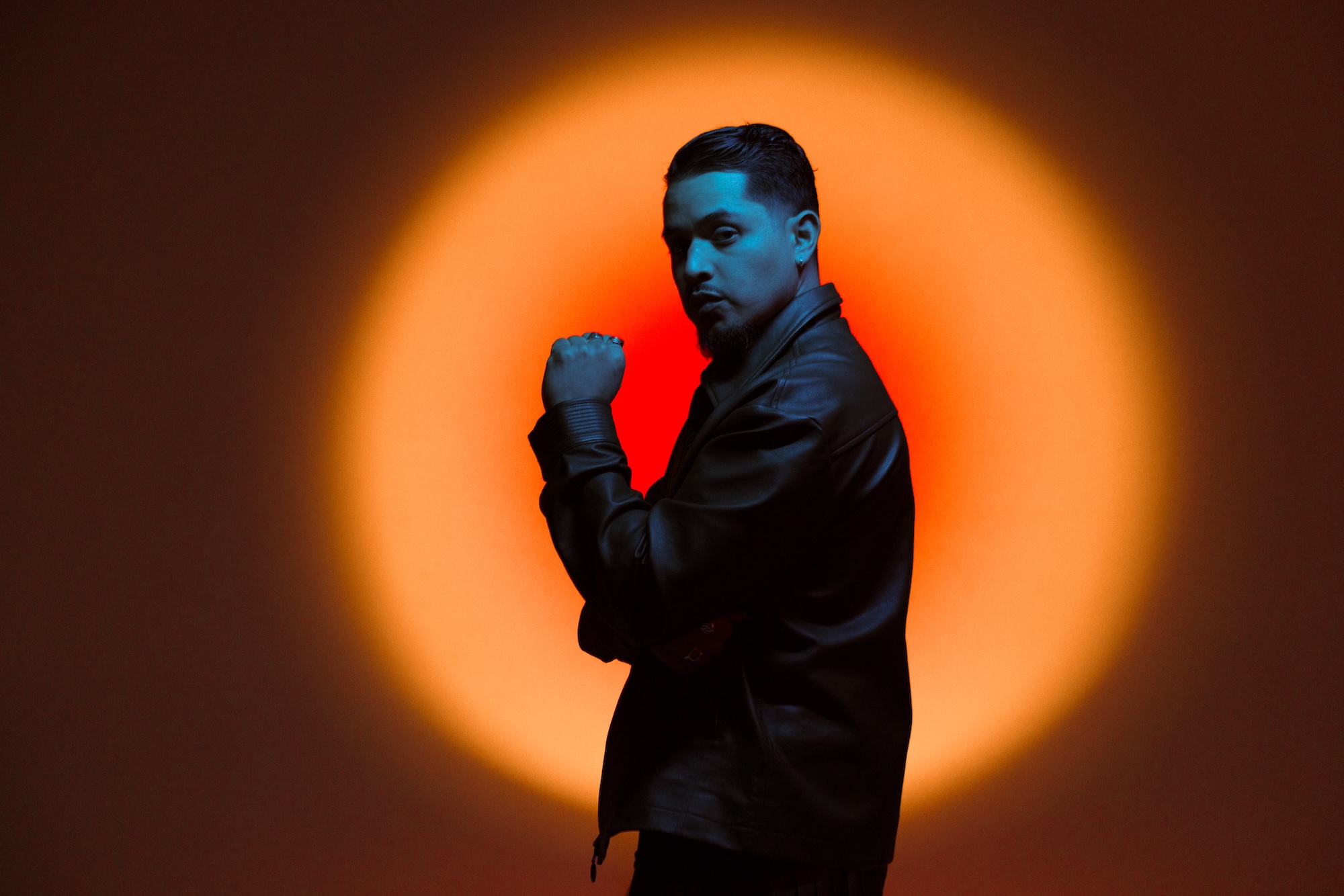 Portrait of a man wearing black against a red background.