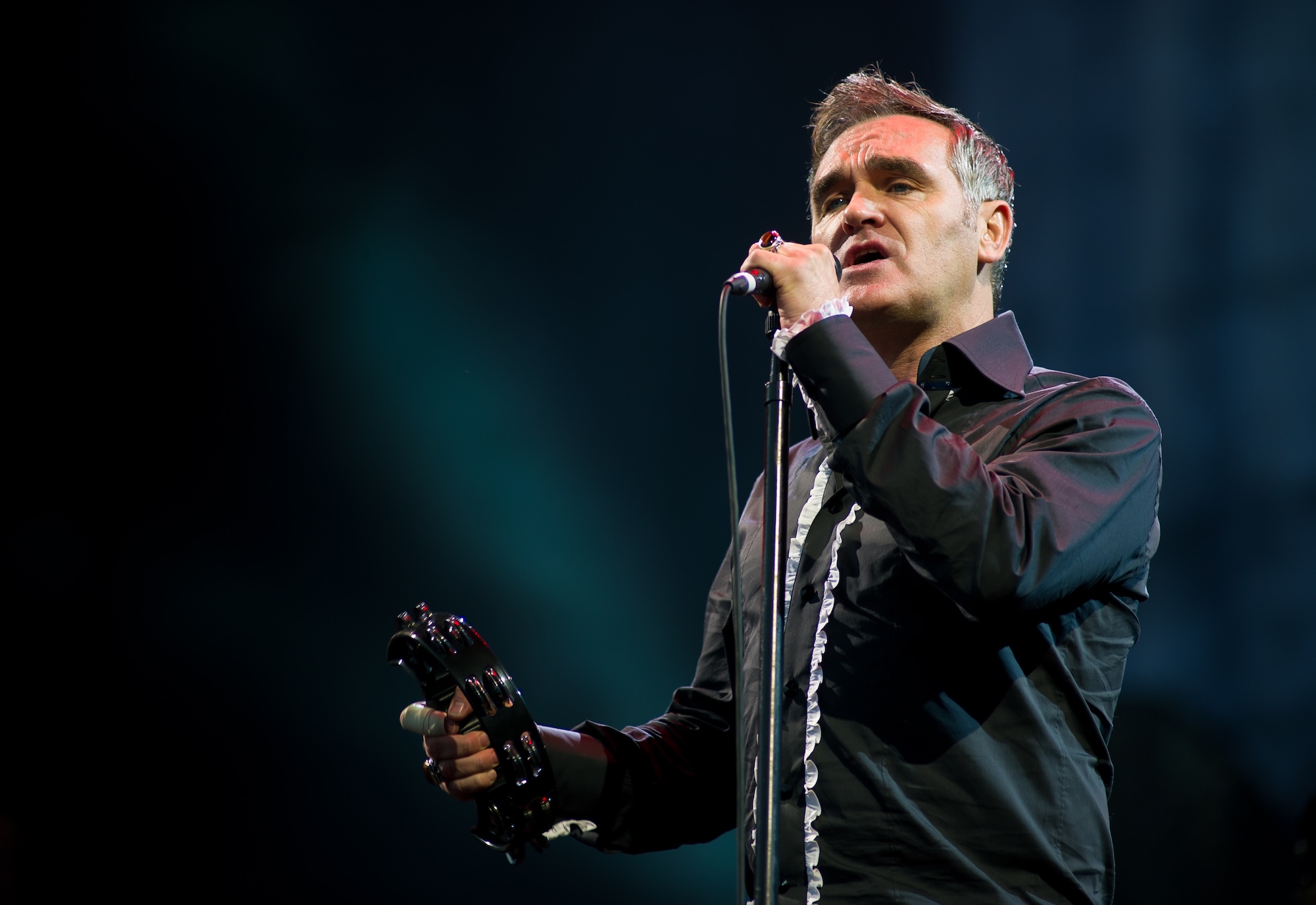 Photo of Morrissey performing on stage wearing a black shirt.