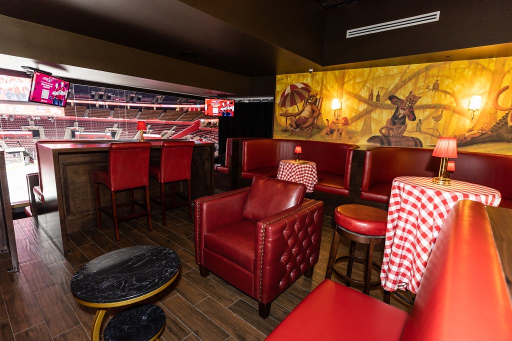 photo of a cozy bar with red-leather chairs, checkered tablecloths, and lamps