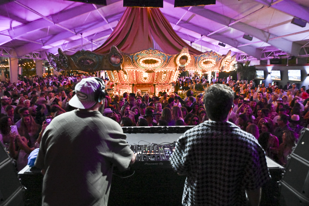 Two DJs performing in front of a carrousel