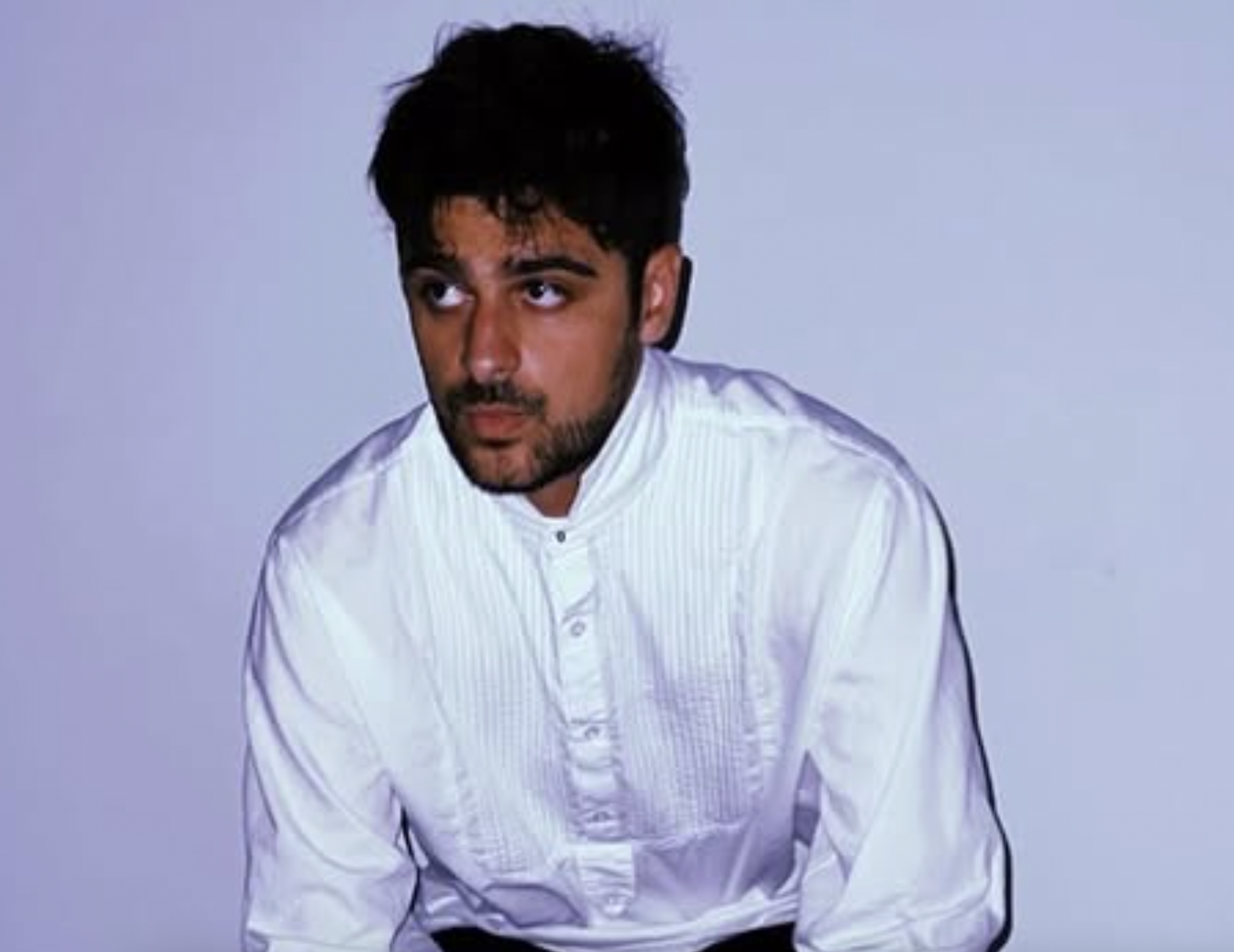 photo of a man in a white-button down shirt against a white wall backdrop