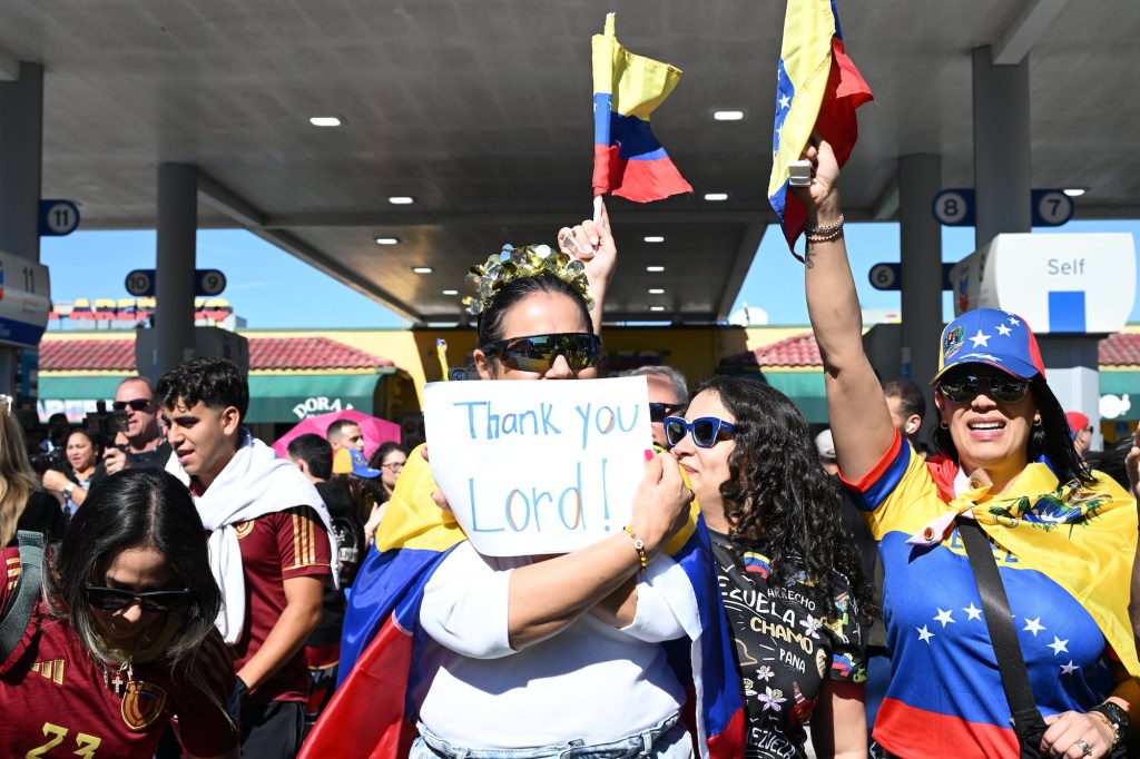 photo of protesters wearing clothes with the Venezuelan flag and waving Venezuelan flags. A woman in the center holds a sign reading, "Thank you Lord"