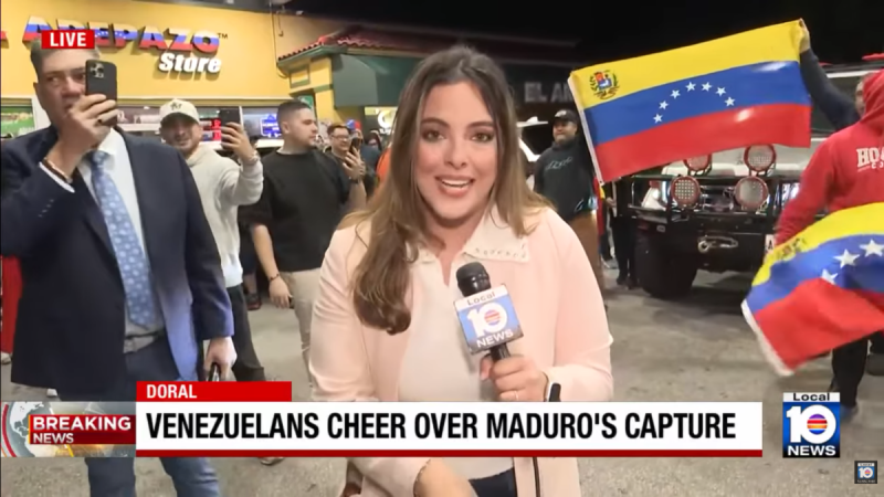 A photo of a TV broadcaster with Venezuelan flags in the background.