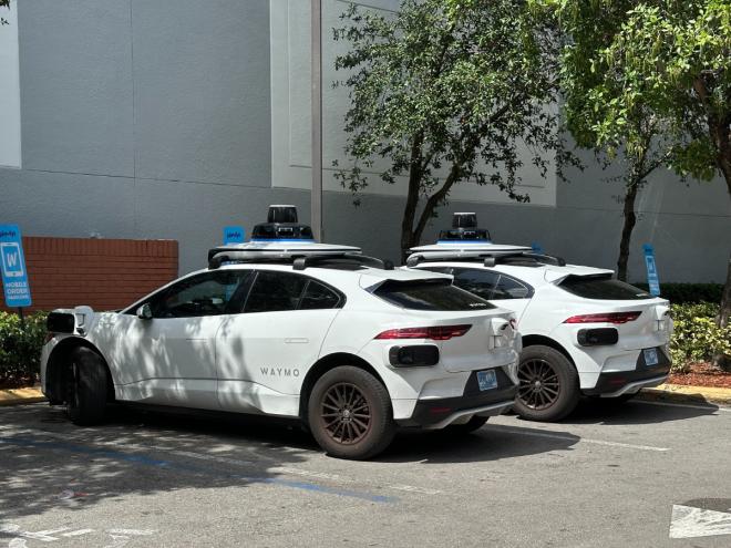 Two white Waymo sedans parked next to each other.