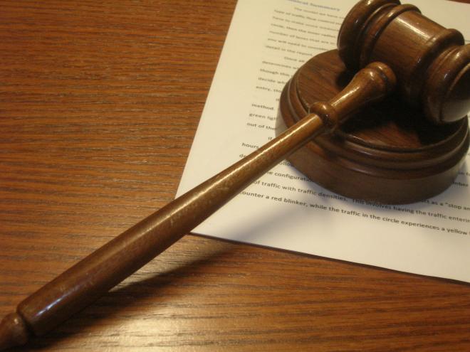 a wooden gavel on a wooden desk on top of some legal paperwork