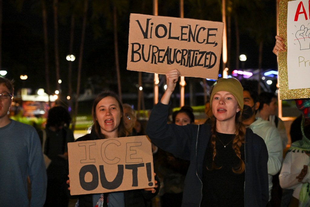photo of protesters holding signs reading, "violence bureaucratized" and "ICE out"