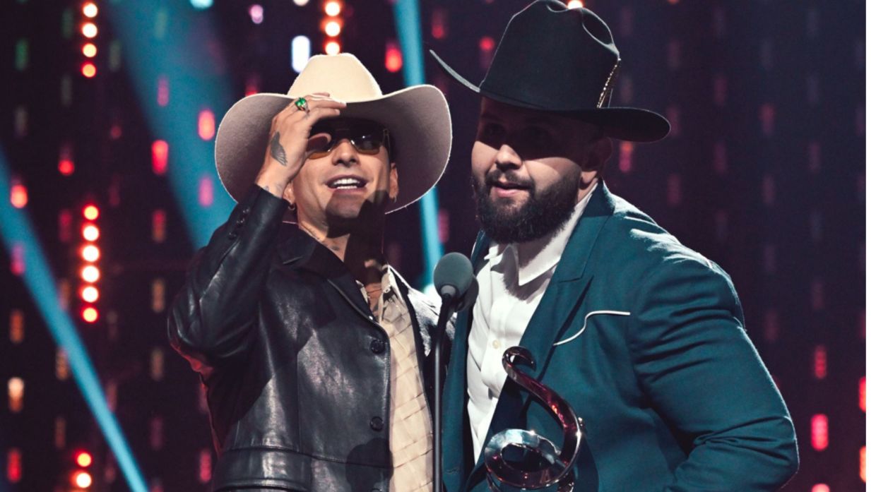 Two men wearing hats on stage receiving an award