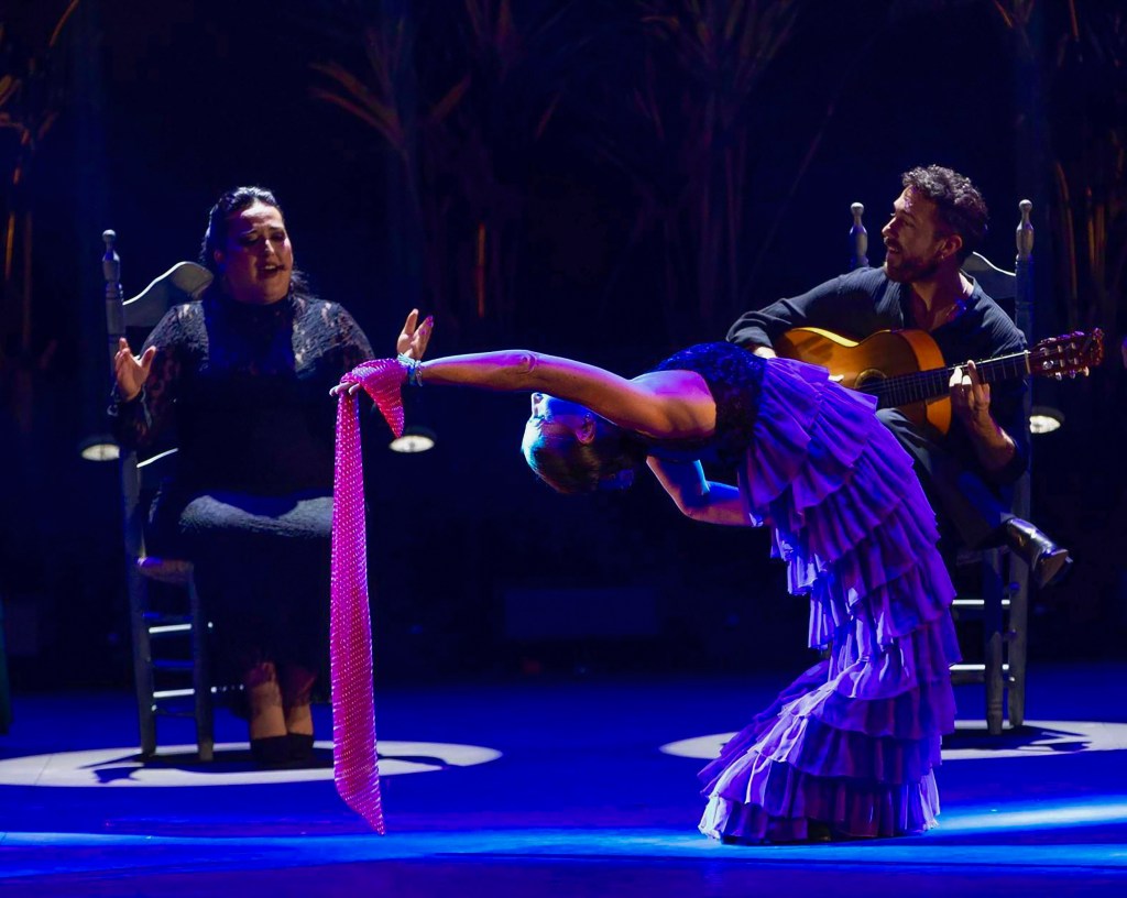 photo of a singer, guitarist, and flamenco dancer performing onstage