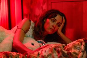 film still of a mother in bed with her child, both bathed in red lighting