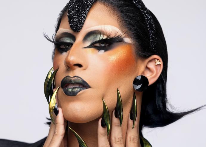 headshot of a drag performer in heavy makeup with dark eyeshadow and lips with pointy nails