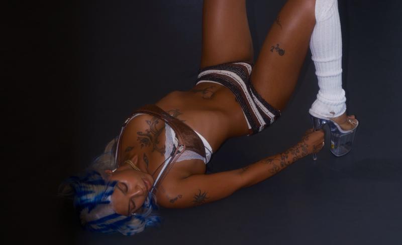 photo of a woman in underwear, leg warmers, and stripper heels lying on the floor of a dance studio