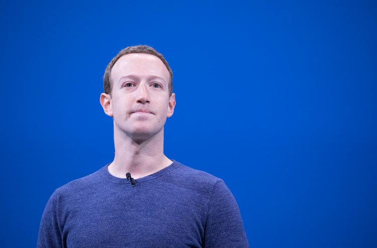 a man in a blue shirt stands with a blank expression