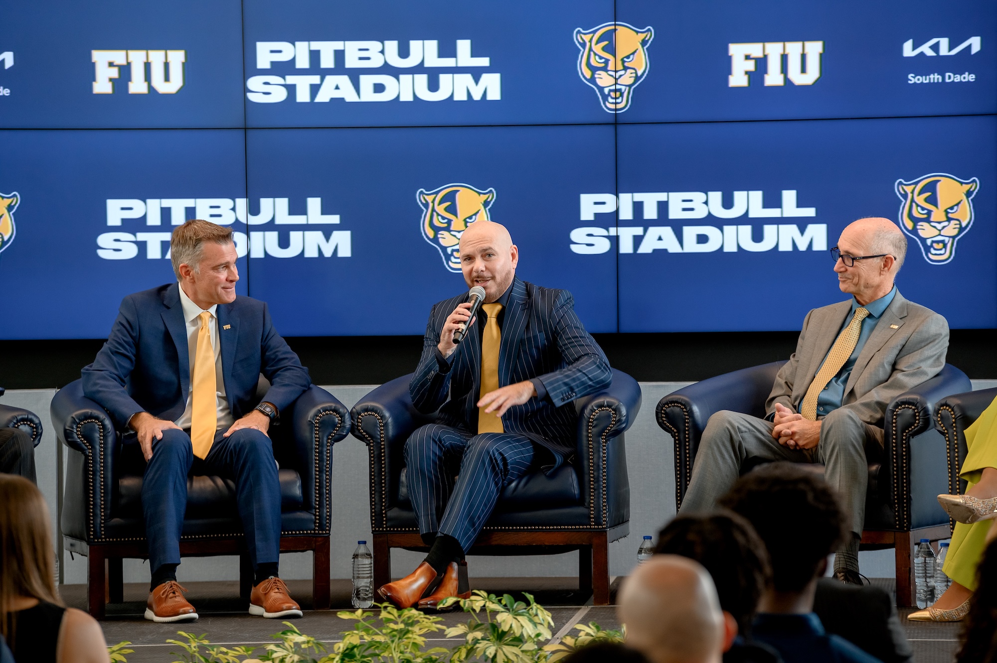 (Left to right) Scott Carr, Pitbull, and Kenneth Jessell speak during the FIU Pitbull Stadium announcement. They are seated in front of a background that says "Pitbull Stadium."