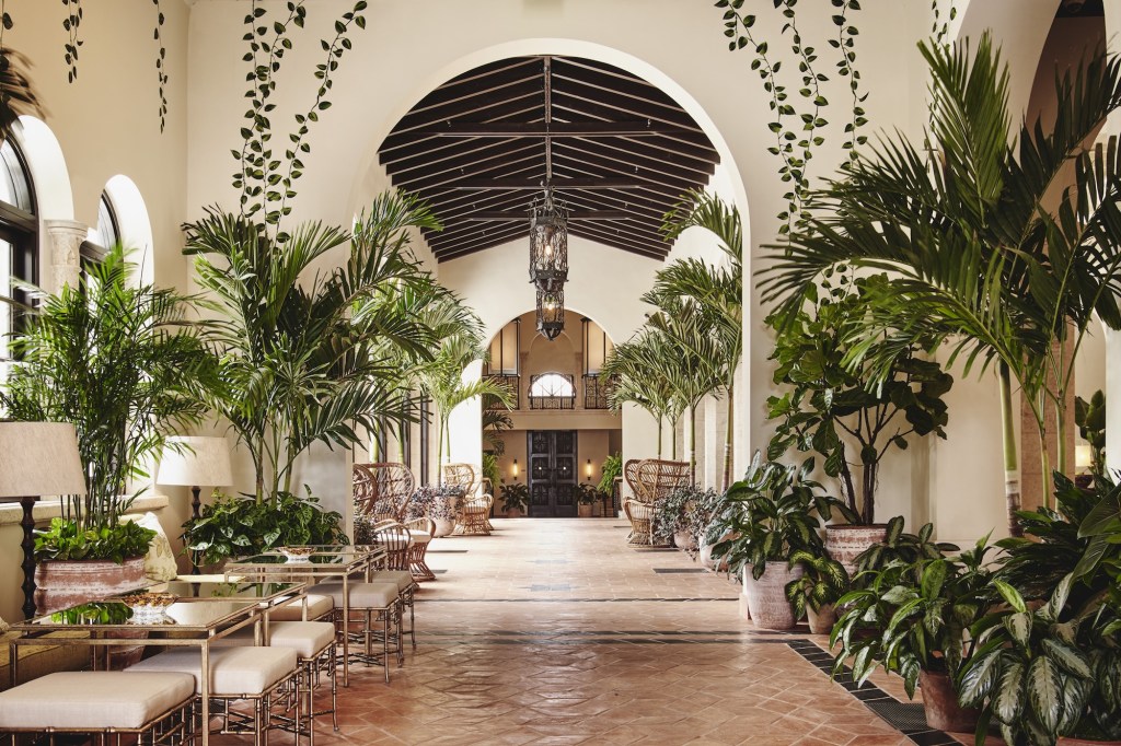 photo of a palatial thoroughfare inside a hotel with lots of seating and plants on either side of the walkway