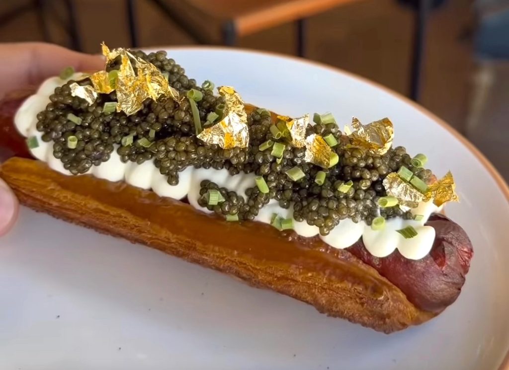The gold foil topped caviar topped corissant hot dog made with Australian Wagyu on a plate