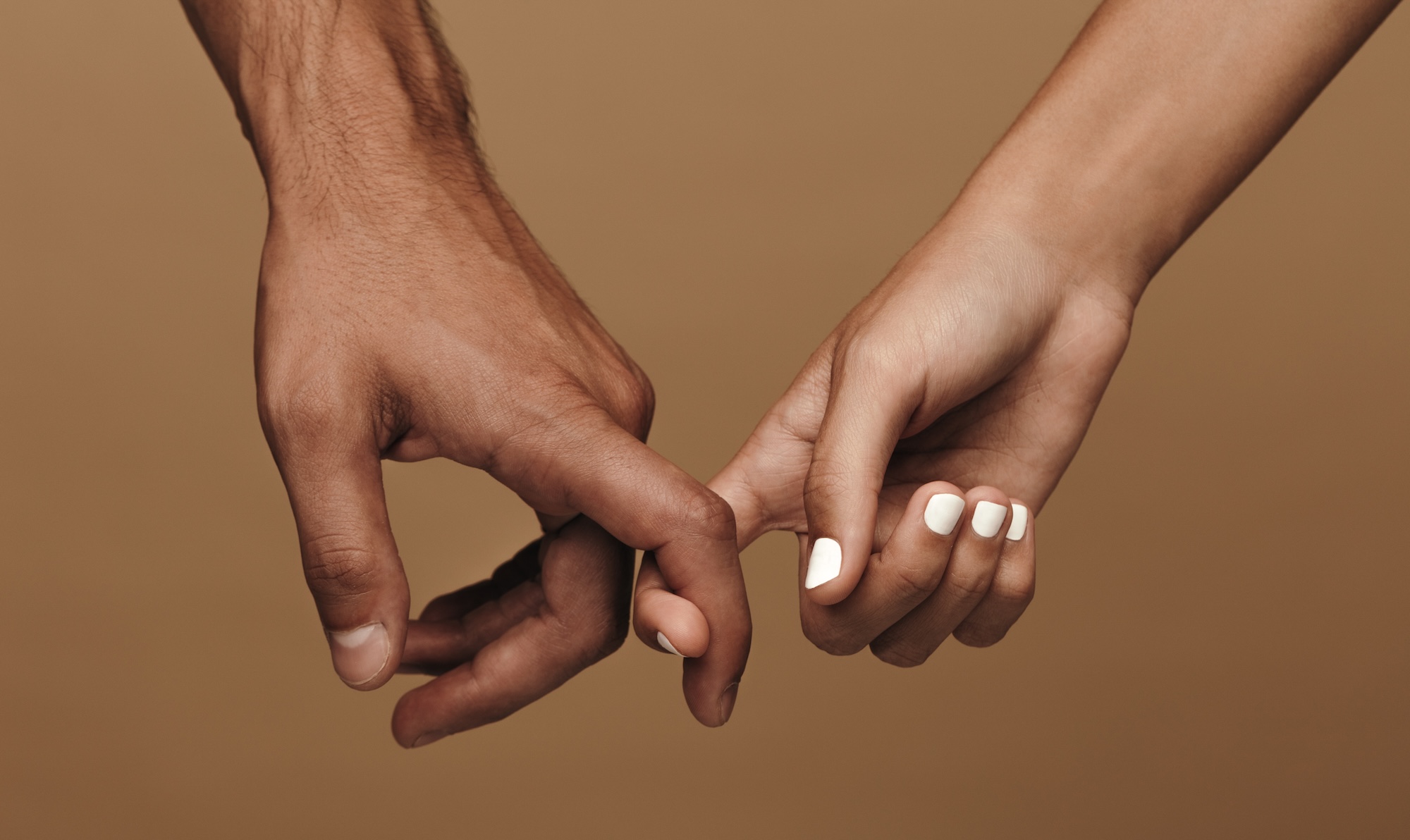 Close-up photo of a couple linking index fingers