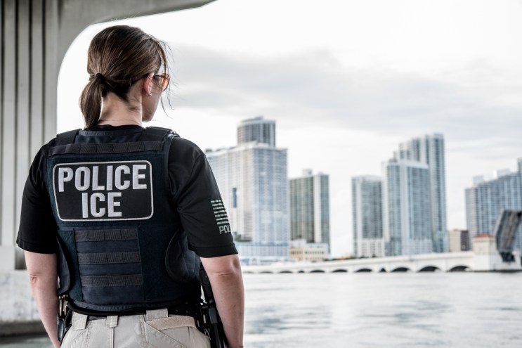 An ICE officer looks out over the Miami skyline.