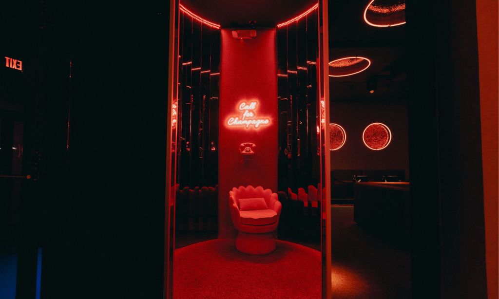 Photo of a small room with a chair and red neon.  