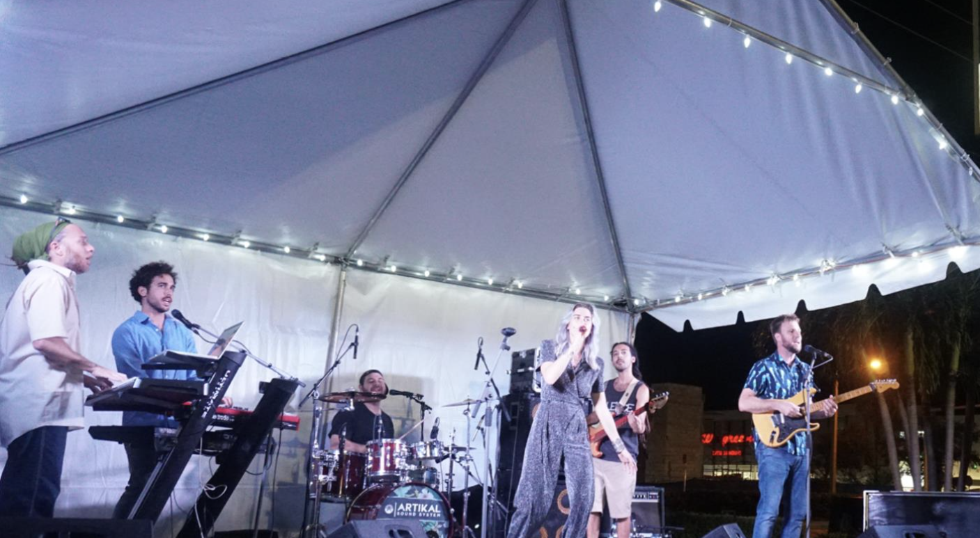 Photo of a band performing at night under a tent in Boynton Beach