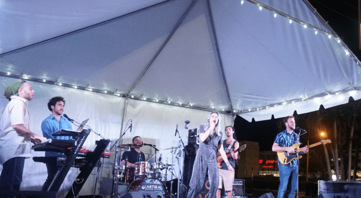 Photo of a band performing at night under a tent in Boynton Beach
