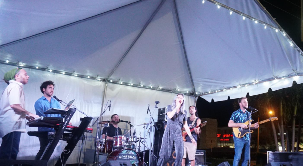 Photo of a band performing at night under a tent in Boynton Beach