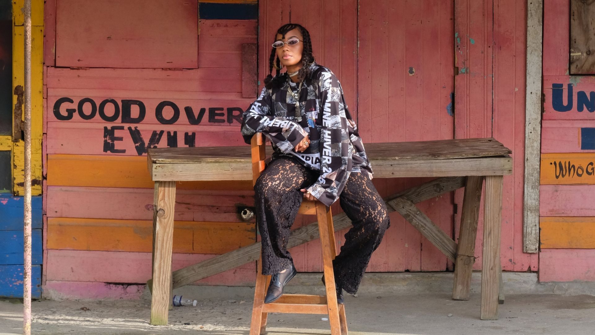 Photo of a woman sitting in front of a colorful wooden building.