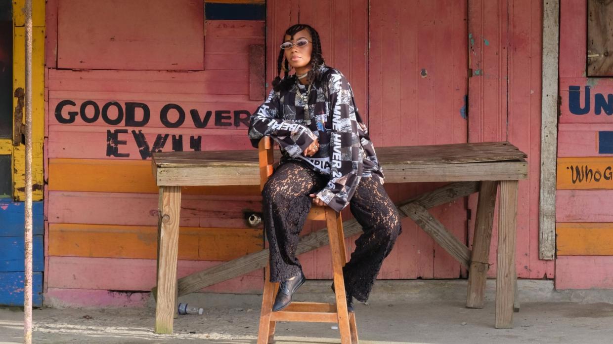 Photo of a woman sitting in front of a colorful wooden building.
