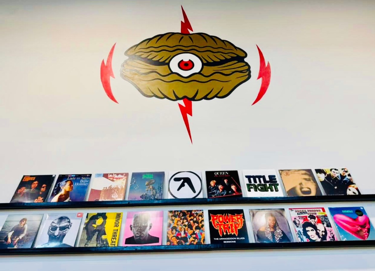 Photo of a wall with a shell-shaped logo and vinyl records.