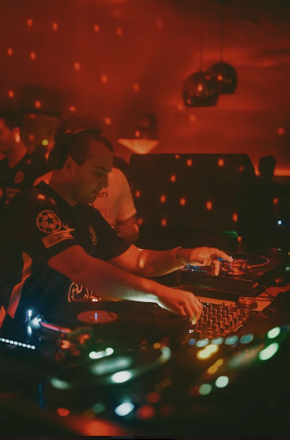 Photo of two Djs performing behind the decks .