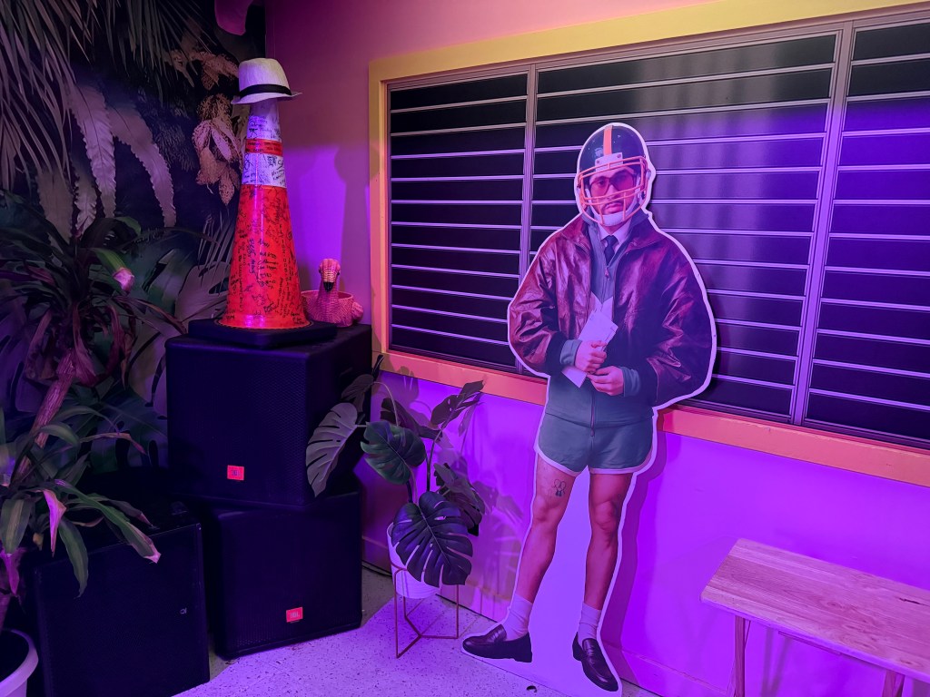 photo of a cardboard cutout of Bad Bunny wearing a football helmet next to a traffic cone with a Panama hat on top of it