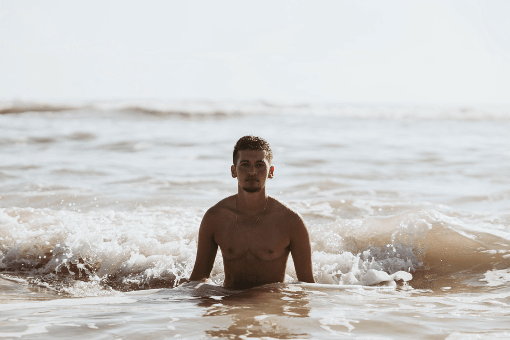 photo of a young man coming out of the ocean in daytime